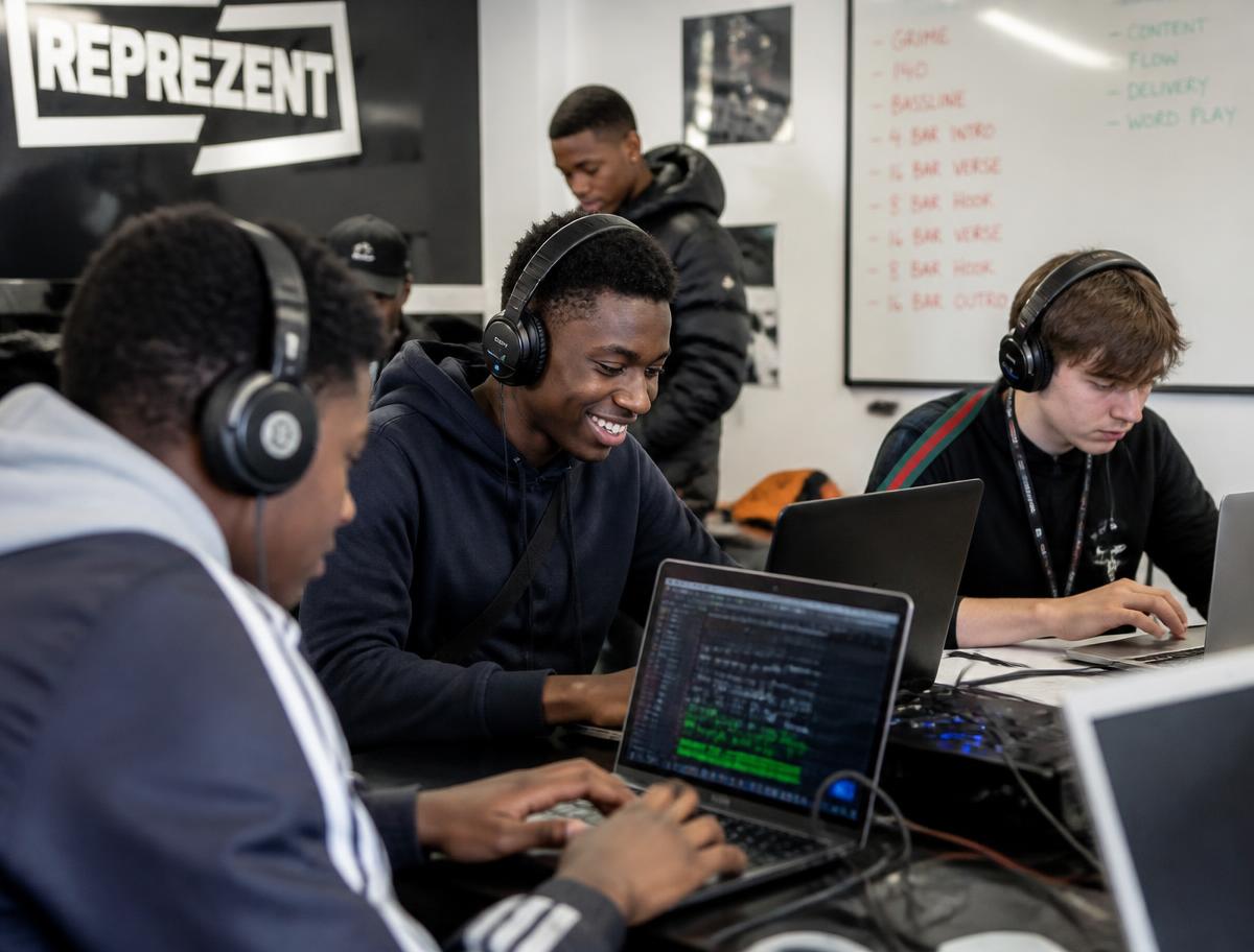 Young people working on laptops in a music and media workshop